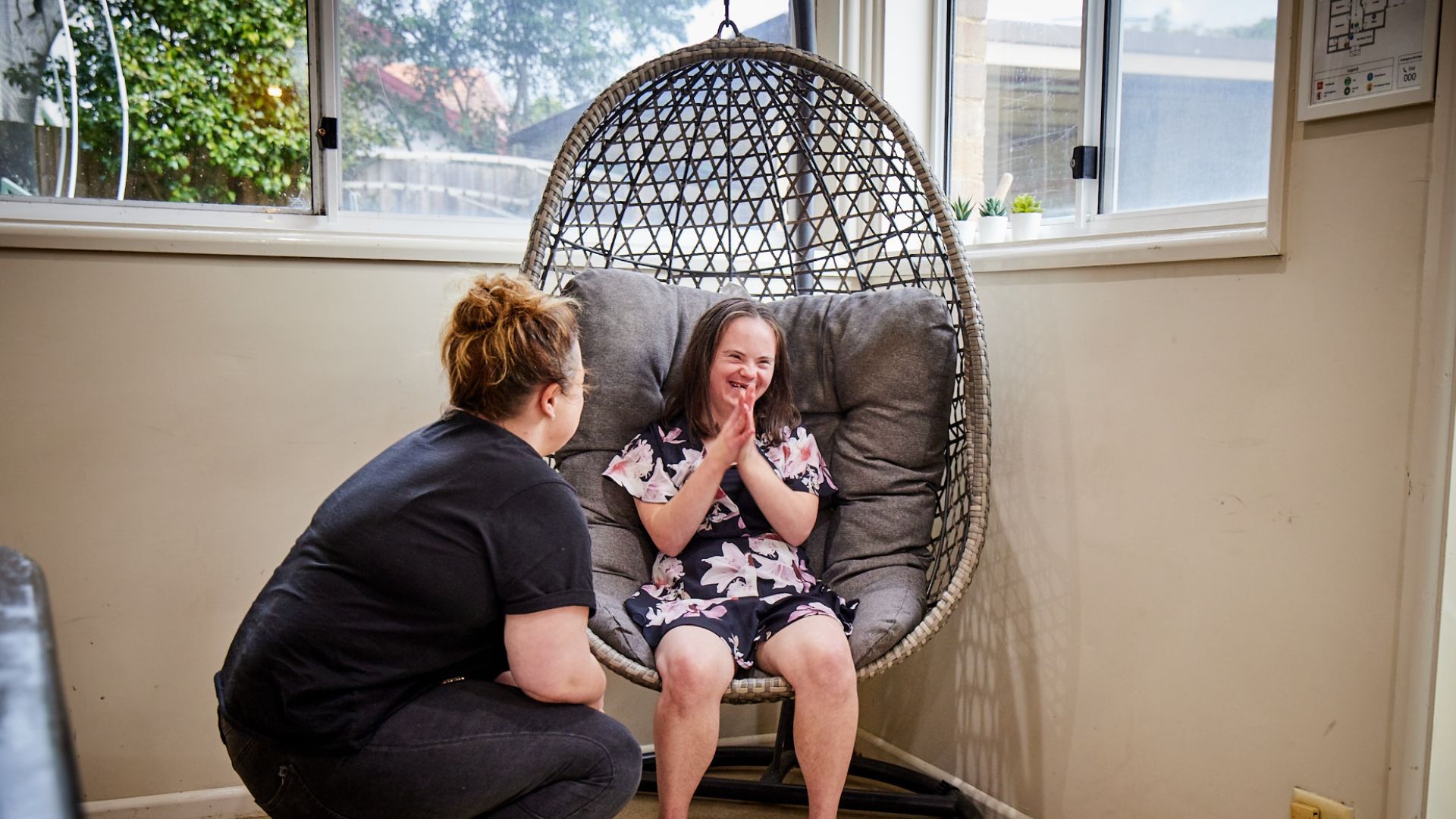 Rose Villa House Manager talks to Base participant sitting in a hanging chair